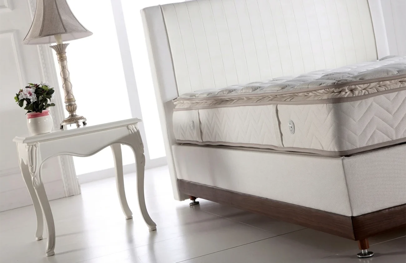 Prim-plan al părții laterale a saltelei Almina cu finisaje decorative și mânere