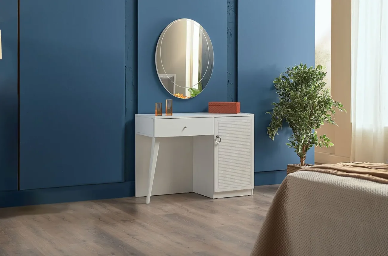 Masă de toaletă Majer albă în interiorul dormitorului cu oglindă rotundă pe fundalul unui perete albastru