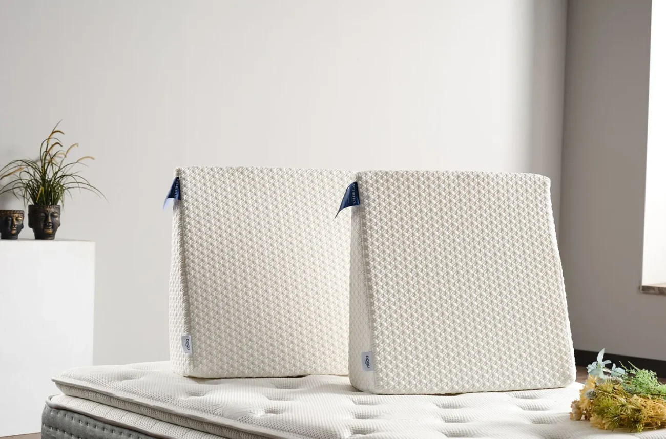 Două perne ortopedice elegante Anti-Reflux așezate vertical pe o saltea în decorul dormitorului