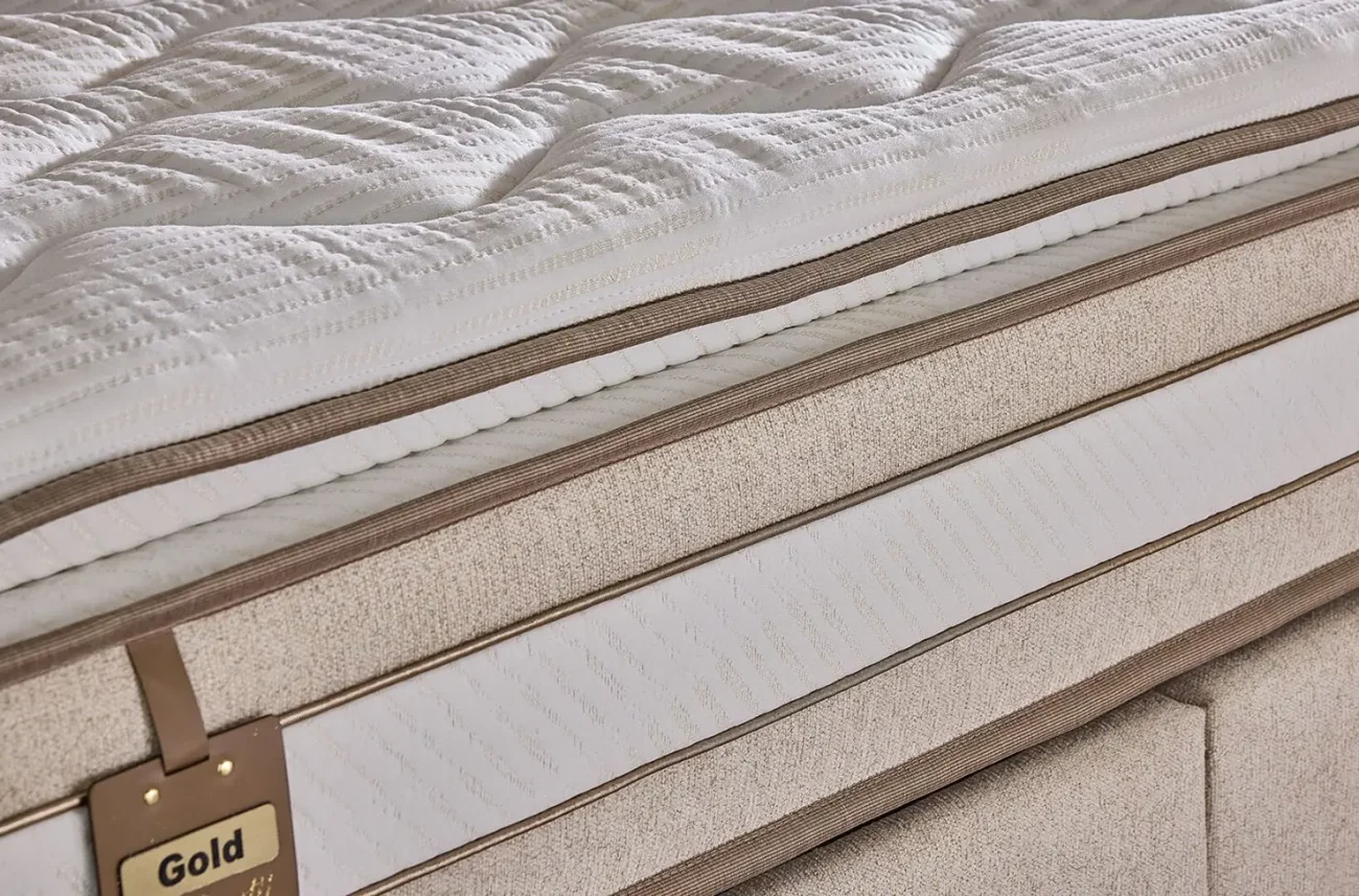 Textura țesăturii de elită a husei saltelei Gold Prestij cu elemente decorative aurii